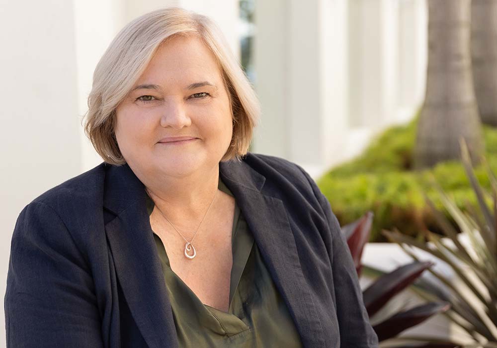Portrait of Louise Dudley, an Executive Coach, smiling in a professional setting with lush greenery in the background.
